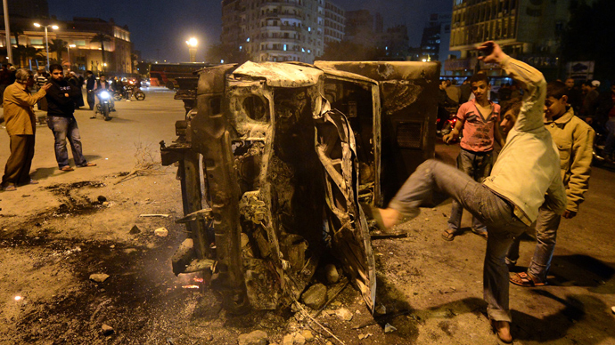 An Egyptian man gives a kick towards a police vehicle that has been burnt by angry protesters following clashes with plainclothes policemen in Cairo’s on Tahrir square on March 3, 2013 (AFP Photo / Khaled Desouki)