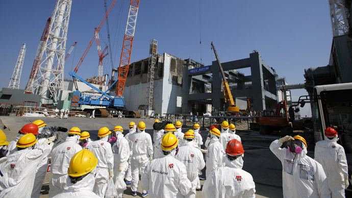 This photo taken on March 6, 2013 shows members of the media wearing protective suits and masks being escorted by Tokyo Electric Power Co (TEPCO) employees as they visit near the No.4 reactor (C) and the construction of a foundation (R) for storage of melted fuel rods at TEPCO's tsunami-crippled Fukushima Dai-ichi nuclear power plant in the town of Okuma, Fukushima prefecture, ahead of the second anniversary of the March 11, 2011 tsunami and earthquake. (AFP Photo/Issei Kato)