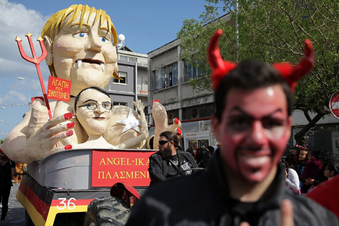 Cypriots walk past a papier-machÈ statue caricaturing German Chancellor Angela Merkel and President of Cyprus Nikos Anastasiadis, in an annual carnival in the southern city of Limassol, March 17, 2013. (AFP Photo / Yiannis Kourtoglou)