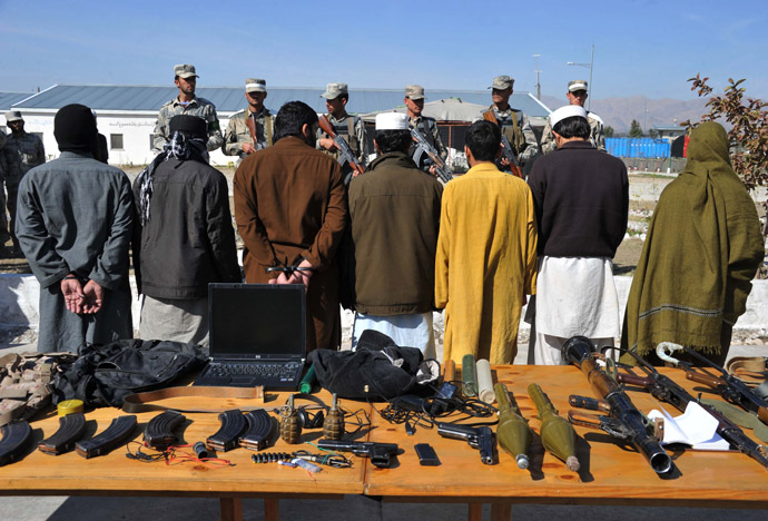 Taliban fighters stand handcuffed near seized weapons as they are displayed to the media at a police headquarters in Jalalabad on March 2, 2013. (AFP Photo/Noorullah Shirzada)