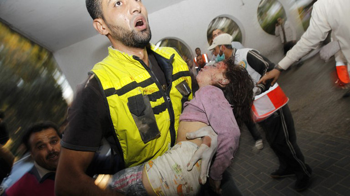 A Palestinian rescue worker carries the body of a child from the al-Dallu family into the hospital in Gaza City on November 18, 2012, after seven members of the al-Dallu family, including four children, were among nine people killed when an Israeli missile struck a family home in Gaza City. (AFP Photo / Mohammed Abed)