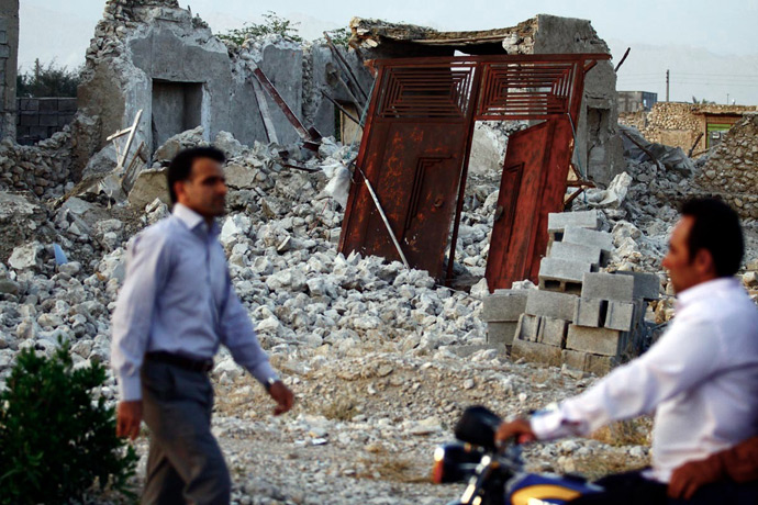 Iranians walk past the ruins of a destroyed house in the town of Shonbeh, southeast of Bushehr, on April 9, 2013 after a powerful earthquake struck near the Gulf port city of Bushehr (AFP Photo / STR)