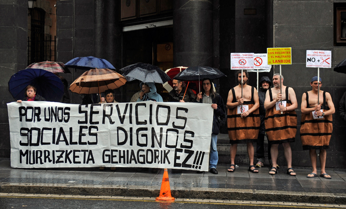 Three men in a barrel costumes hold placards against government's social cuts during a protest called by several social groups in front of the ruling Basque Nationalist Party (PNV) headquarters in the northern Spanish city of Bilbao on May 2, 2013 (AFP Photo / Rafa Rivaz)