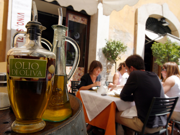 Diners sit near bottles of olive oil at a restaurant in Rome (Reuters / Dario Pignatelli)