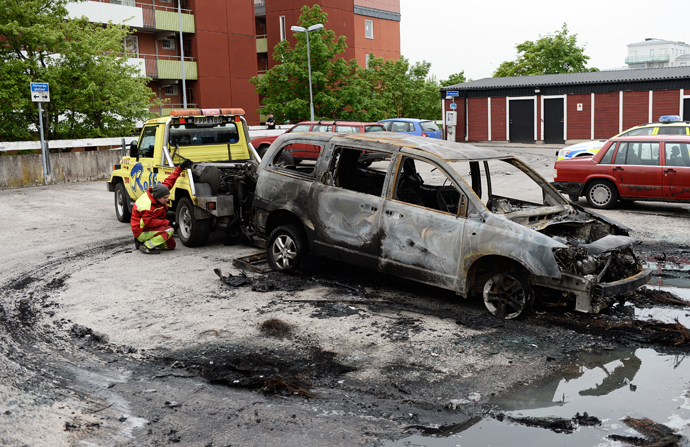  A burned-out van is prepared for removal after youths rioted in Husby, northern Stockholm on May 21, 2013 (AFP Photo / Jonathan Nackstrand) 