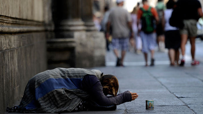 : Tourist pass by a street beggar in central Rome.(AFP Photo / Filippo Monteforte) 
