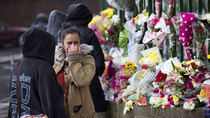 A woman reacts as she looks at floral tributes left at the scene where Drummer Lee Rigby of the 2nd Battalion was killed outside Woolwich Barracks in London on May 24, 2013 (AFP Photo / Justin Tallis) 