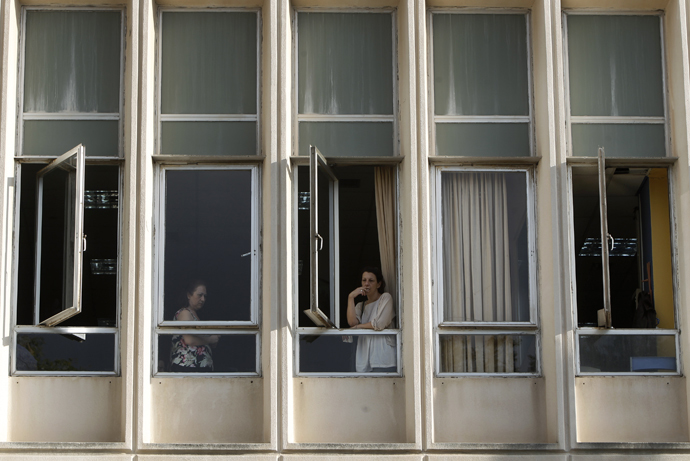 Um funcionário fuma um cigarro em uma janela da sede da ERT televisão estatal grega após o anúncio do governo de que ele será desligado da emissora em Atenas, 11 de junho de 2013. (Reuters / John Kolesidis)