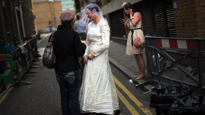 A man wearing a wedding dress speaks with other royal supporters during a wedding street party in London.(AFP Photo / Dinitar Dilkoff)