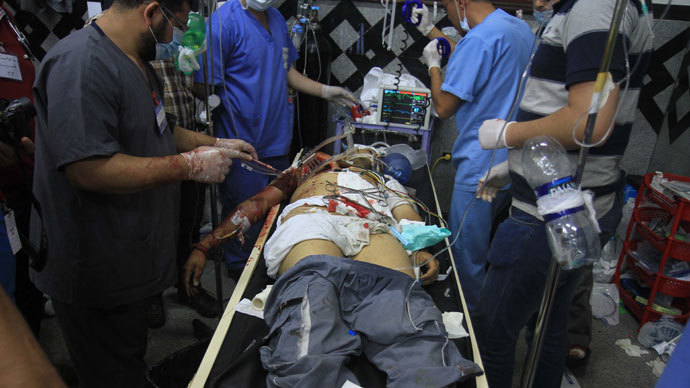 An injured Egyptian supporter (C) of the deposed Egyptian president Mohamed Morsi is given medical aid by doctors in a field hospital after clashes with riot policemen in Cairo early on July 27, 2013.(AFP Photo / Ahmed Mahmud)