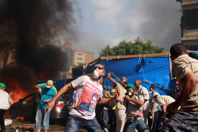 Supporters of the Muslim Brotherhood and Egypt's ousted president Mohamed Morsi throw stones during clashes with security forces in Cairo on August 14, 2013, as security forces backed by bulldozers moved in on two huge pro-Morsi protest camps, launching a long-threatened crackdown that left dozens dead. (AFP Photo)