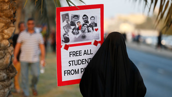 An anti-government protester holds up a sign with photos of students detainees that read, "Free All Students from Prison" as she walks to the female area during a rally organized by Bahrain's main opposition party Al Wefaq on Budaiya highway west of Manama, August 23, 3013.(Reuters / Hamad I Mohammed)