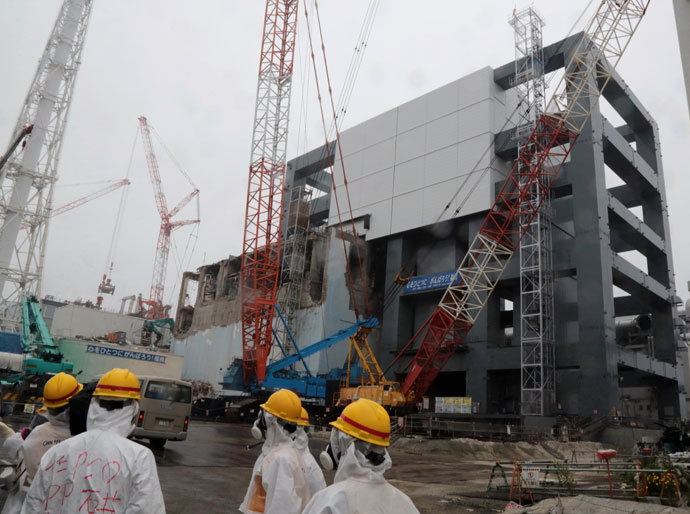 Reporters and Tokyo Electric Power Co workers look up the unit 4 reactor building during a media tour at TEPCO's Fukushima Dai-ichi nuclear plant in the town of Okuma, Fukushima prefecture in Japan on June 12, 2013.(AFP Photo / Noboru Hashimoto)