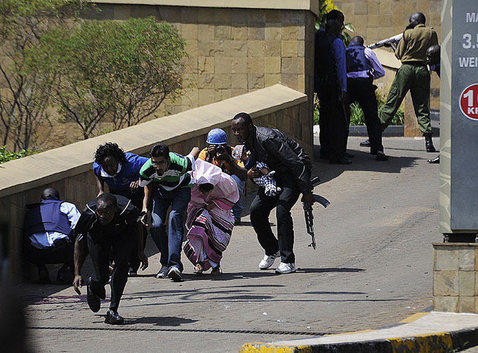 A policeman carry's a baby to safety after masked gunmen stormed an upmarket mall and sprayed gunfire on shoppers and staff, killing at least six on September 21, 2013 in Nairobi. (AFP Photo / Simon Maina)