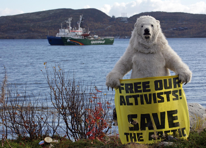 Greenpeace activist dressed as a polar bear holding a banner in front of the Arctic Sunrise Greenpeace's Arctic protest ship in Kola Bay at the military base Severomorsk on the Kola peninsula on September 24, 2013 (AFP Photo / Greenpeace / Igor Podgorny)