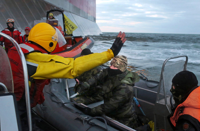Camouflage clad mask wearing officer of Russian Coast Guard (C) pointing a knife at a Greenpeace International activist (L) during an environmentalists' attempt to climb Gazprom’s ‘Prirazlomnaya’ Arctic oil platform somewhere off Russia north-eastern coast in the Pechora Sea on September 18, 2013 (AFP Photo / Greenpeace / Denis Sinyakov)