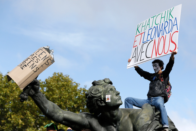 A man holds a sign which reads "Khatchik and Leonarda with us" as he stands on the statue at the Place de la Nation during a protest demonstration with French high school students in Paris October 18, 2013 (Reuters / Gonzalo Fuentes)