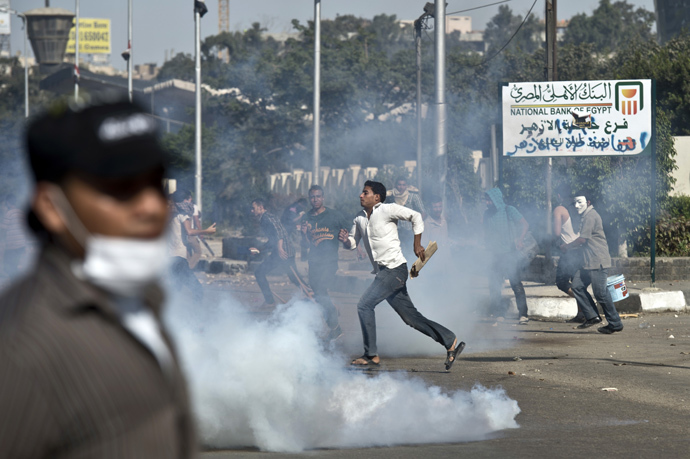 Egyptian students of al-Azhar university run for cover from a tear gas canister fired by riot police during clashes outside their university campus in Cairo on October 20, 2013 following an anti-army protest (AFP Photo / Khaled Desouki) 