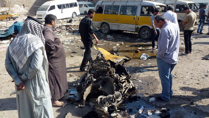 Iraqis look at the remains of a vehicle following an explosion at a small bus station on October 27, 2013, in the the Mashtal district of the capital Baghdad (AFP Photo / Sabah Arar)