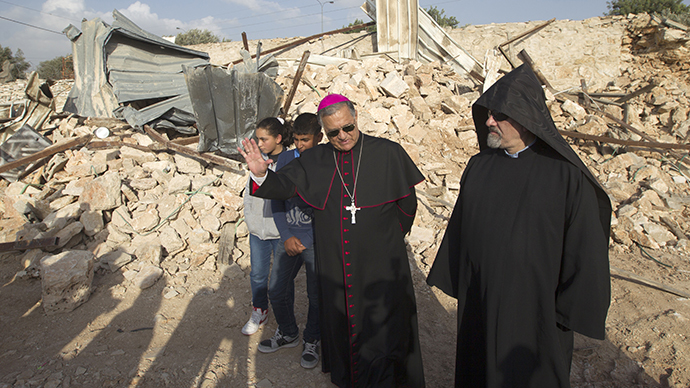 Children look on as Latin Patriarch of Jerusalem Fouad Twal (C) stands amongst the ruins of a Palestinian home, on November 5, 2013. (AFP Photo / Ahmad Gharabli)