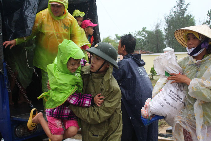 A soldier assists a young girl as villagers are evacuated to a safe place by a military truck in preparation for the arrival of the super typhoon Haiyan in the central province of Quang Nam on November 9, 2013.(AFP Photo / STR)