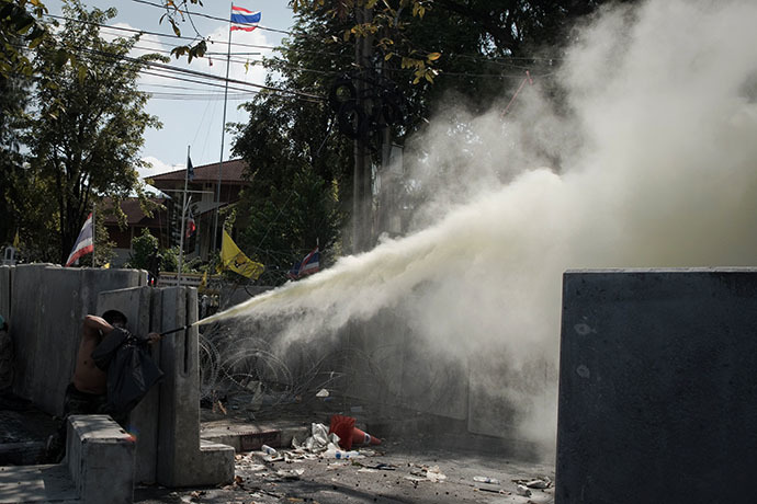 An anti-government protester throw smoke to the police outside Governement House during a demonstration in Bangkok on December 1, 2013. (AFP Photo / Nicolas Asfouri)