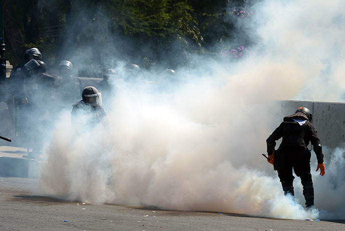 Thai riot policemen collect tear gas from anti-government protesters during demonstration at Governement House during a demonstration in Bangkok on December 1, 2013. (AFP Photo / Pornchai Kittiwongsakul)