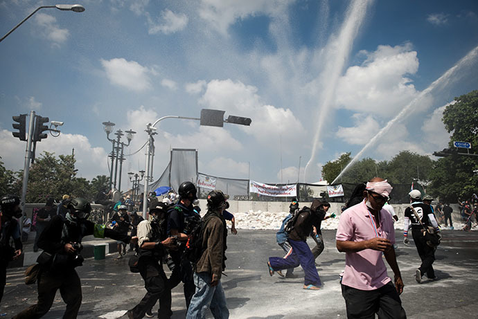 Anti-government protesters and the media run from water canons outside Governement house during a demonstration in Bangkok on December 1, 2013. (AFP Photo / Nicolas Asfouri)