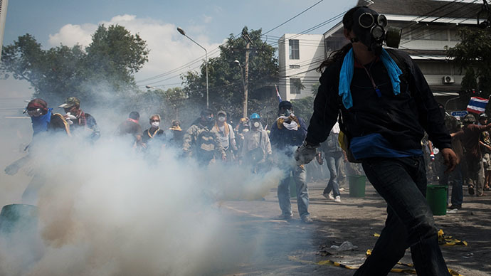 An anti-government protester throws a tear gas back to the police outside Governement House during a demonstration in Bangkok on December 1, 2013. (AFP Photo / Nicolas Asfouri)