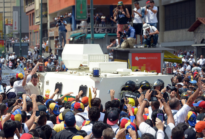 Kannattajat Leopoldo Lopez, kiihkeä vastustaja Venezuelan sosialistinen hallitus edessään pidätysmääräyksen jälkeen, kun presidentti Nicolas Maduro määräsi hänet pidätettiin syytettynä murhasta ja väkivaltaan yllyttämisestä, ympäröivät National Guard ajoneuvo ajaa Lopez pois, kun hän kääntyi vuonna mielenosoituksessa Caracasissa 18 helmikuu 2014.  (AFP Photo / Raul Arboleda)