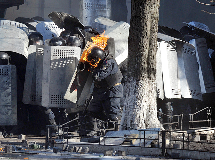 A photo taken on Febraury 18, 2014 shows a riot police whose helmet is burning, shielding himself during clashes with anti-government rioters in central Kiev. (AFP Photo / Genya Savilov)