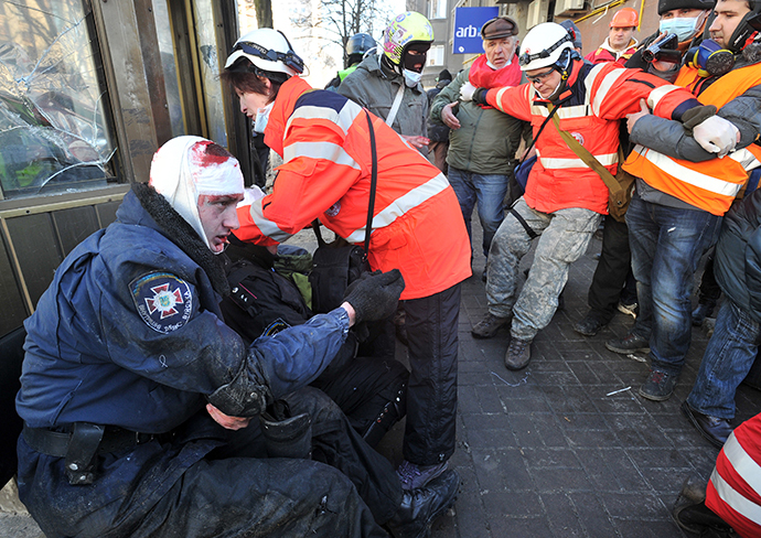 Red Cross workers give first aid to policemen wounded during clashes with anti-government rioter in Kiev on February 18, 2014. (AFP Photo / Genya Savilov)