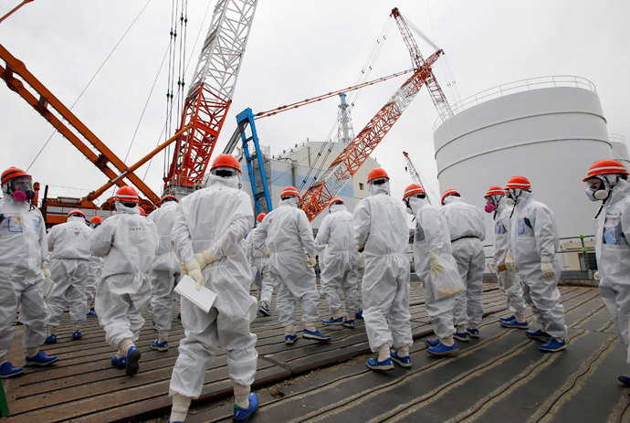 Members of the media and Tokyo Electric Power Co. (TEPCO) employees wearing protective suits and masks walk toward the No. 1 reactor building at the tsunami-crippled TEPCO's Fukushima Daiichi nuclear power plant in Fukushima prefecture March 10, 2014.(Reuters / Toru Hanai)