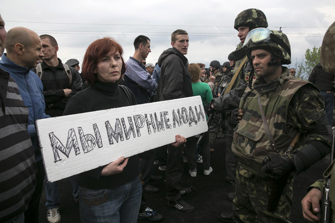 A civilian holds a sign in front of Ukrainian troops at a checkpoint near the town of Slaviansk in eastern Ukraine May 2, 2014. The sign reads, "We are peaceful people." (Reuters/Baz Ratner)