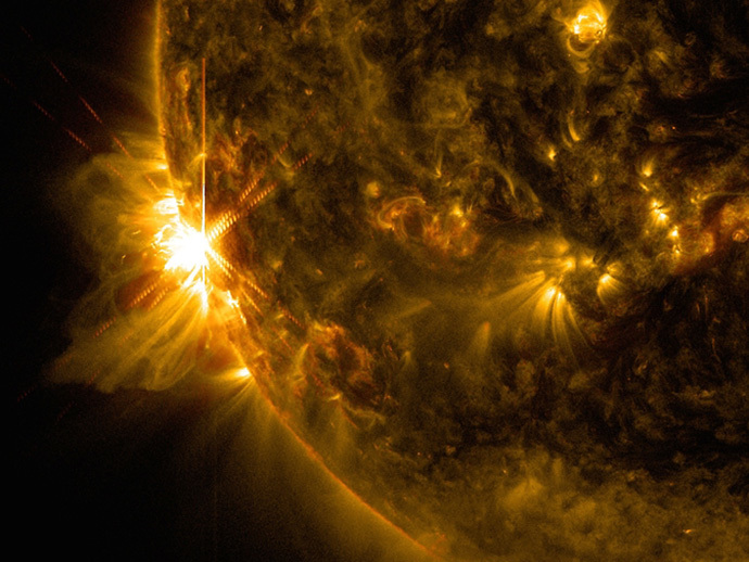 Uma explosão solar explode fora o membro esquerdo do sol nesta imagem capturada pelo Solar Dynamics Observatory da NASA em 10 de Junho de 2014 às 07:41 EDT.  Este é classificado como um surto X2.2, mostrado em uma mistura de dois comprimentos de onda de luz: 171 e 131 angstroms, colorizado em ouro e vermelho, respectivamente.  (Crédito da Imagem: NASA / SDO / Goddard / Wiessinger)
