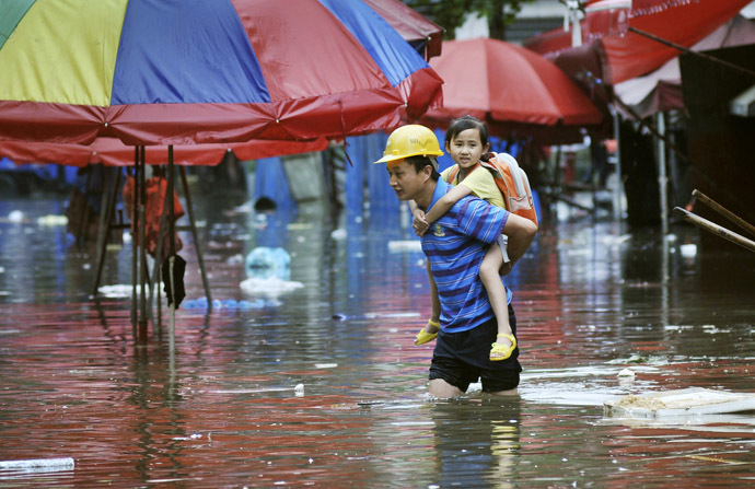 A man carries a girl on his back as he wades through a flooded street after heavy rainfalls hit Changsha, Hunan province June 20, 2014. (Reuters)