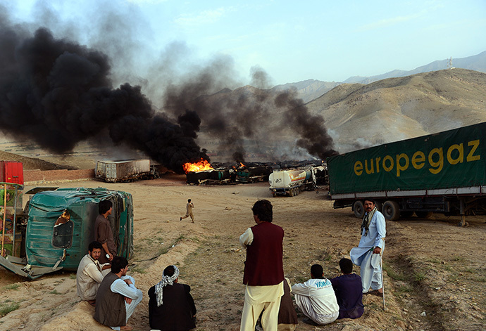 Afghan residents look on as smoke rises from buring fuel trucks following an overnight attack by Taliban militants in Chawk-e-Arghandi on outskirts of Kabul on July 5, 2014. (AFP Photo / Wakil Kohsar)