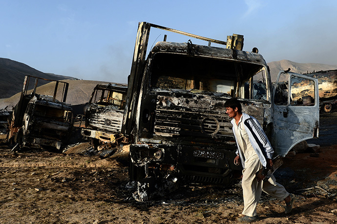 An Afghan resident walks past burned-out fuel trucks following an overnight attack by Taliban militants in Chawk-e-Arghandi on outskirts of Kabul on July 5, 2014. (AFP Photo / Wakil Kohsar)