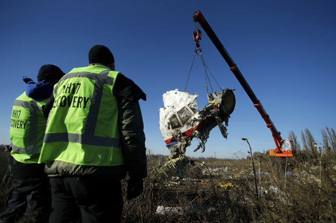 Investigators watch as a piece of wreckage from the Malaysia Airlines flight MH17 is transported at the site of the plane crash near the village of Hrabove (Grabovo) in Donetsk region, eastern Ukraine November 20, 2014. (Reuters/Antonio Bronic)