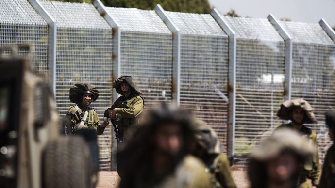 Israeli soldiers stand guard as Syrian residents (unseen) approach the Syria-Israel border in the Israeli annexed Golan Heights, near the southern Syrian village of Ar Rafide, on May 7, 2013.(AFP Photo / Menahem Kahana)