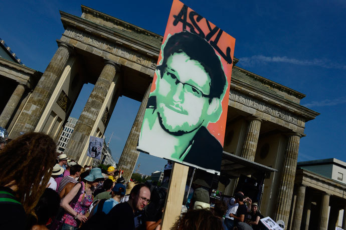 Demonstrators hold up a placard in support of former US agent of the National Security Agency, Edward Snowden in front of Berlin's landmark Brandenburg Gate as they take part in a protest against the US National Security Agency (NSA) collecting German emails, online chats and phone calls and sharing some of it with the country's intelligence services in Berlin on July 27, 2013.(AFP Photo / John Macdougall)