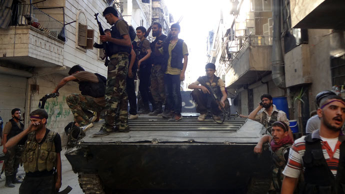 Syrian rebel fighters gather around a former Syrian army tank as rebels prepare to attack positions held by the Syrian army areas in the Salaheddine neighborhood of Aleppo, on July 8, 2013.(AFP Photo / Abo Mhio)
