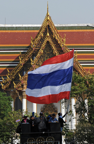 A Thai anti-government protester waves a national flag as he stands on a truck during a protest march through the streets of Bangkok on January 9, 2014 (AFP Photo / Christophe Archambault)