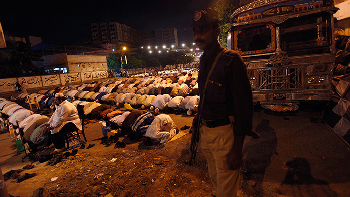 A policeman stands guard as men attend an evening mass prayer session called 