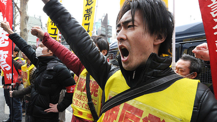 Fukushima nuclear workers and their supporters shouts slogans as they raise their fists in front of the headquarters of Tokyo Electric Power Company (TEPCO), operator of the tsunami-battered Fukushima Daiichi nuclear power plant, during a rally in Tokyo on March 14, 2014. (AFP Photo / Toru Yamanaka)
