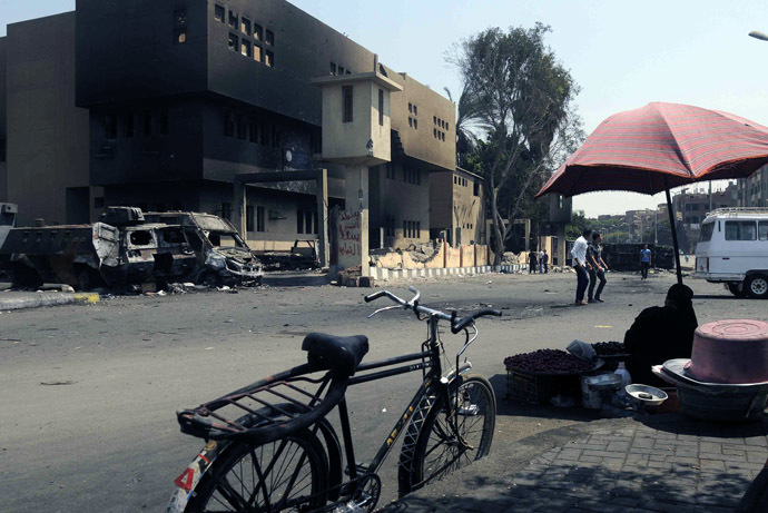  An Egyptian street vendor sits opposite a torched and vandalized police station on August 24, 2013 in the Kirdasah neighbourhood of Giza, on the outskirts of Cairo, that was attacked on August 14, resulting in the death of at least seven policemen following a crackdown by Egyptian security forces on protest camps and sit-ins held by supporters of the Muslim Brotherhood and ousted president Mohamed Morsi.(AFP Photo)