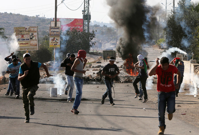 Palestinians run to take cover from tear gas fired by Israeli security forces during clashes following the funeral of Palestinian-American Orwa Hammad on October 26, 2014 in the West bank village of Silwad, near Ramallah. (AFP Photo / Abbas Momani)